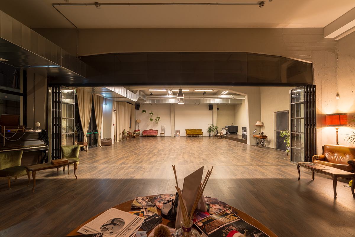 La sala grande vista dalle porte scorrevoli aperte, con la batteria e il palco in fondo.
